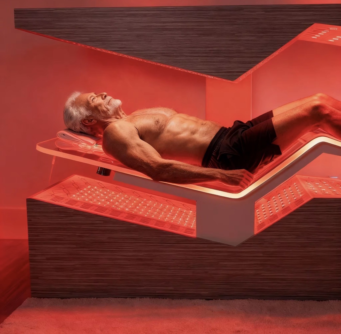 A person reclined on The Immortal during a red light and near-infrared session